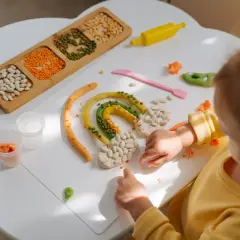 Dziecko tworzy tęczę z plasteliny i ziaren. Wspaniałe zabawy sensoryczne rozwijają kreatywność.