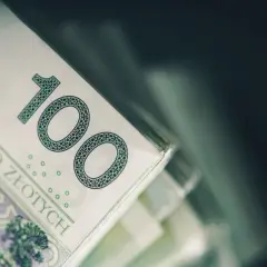 Stos banknotów 100 zł. Czy to zapowiedź dodatkowych 200 zł do emerytury za dzieci?