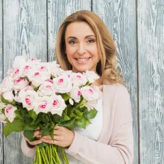 Uśmiechnięta blondynka z bukietem jasnoróżowych róż, gotowa na imieniny Jana.