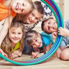 Uśmiechnięte dzieci bawią się kolorowymi obręczami, tworząc radosne zabawy ruchowe dla dzieci.