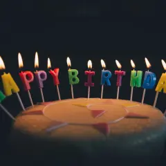 Płonące świeczki z literami tworzą napis "Happy Birthday". Idealne życzenia urodzinowe po angielsku na torcie.