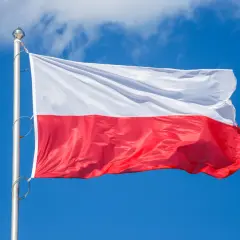 Biało-czerwona flaga Polski powiewa na maszcie na tle błękitnego nieba. 16 maja święto, dzień dumy narodowej.