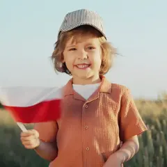 Uśmiechnięty chłopiec w czapce trzyma polską flagę. To radosny dzień, jakby 11 lipca święto narodowe.
