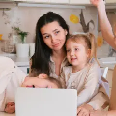 Mama z trójką dzieci przy laptopie. Czy to przyszły dodatek do emerytury za urodzenie 3 dzieci?