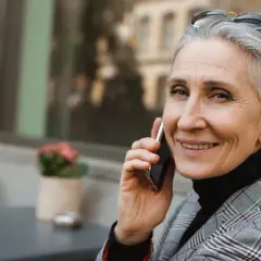 Uśmiechnięta Grażyna rozmawia przez telefon, ciesząc się swoim imieninowym dniem.