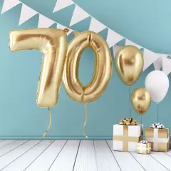 Złote balony z cyfrą 70, prezenty i girlanda tworzą radosną atmosferę. Idealne życzenia na 70 urodziny!