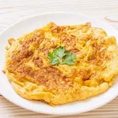 Złocisty omlet na talerzu, idealny jako omlet dla niemowlaka. Delikatny, puszysty, z gałązką pietruszki.