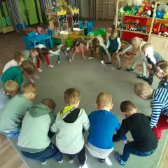 Dzieci w przedszkolu biorą udział w zabawach integracyjnych, tworząc krąg i wykonując ćwiczenia.