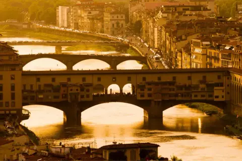 Florencja 18 maja. Złote światło zalewa Ponte Vecchio i rzekę Arno, tworząc malowniczy widok miasta.