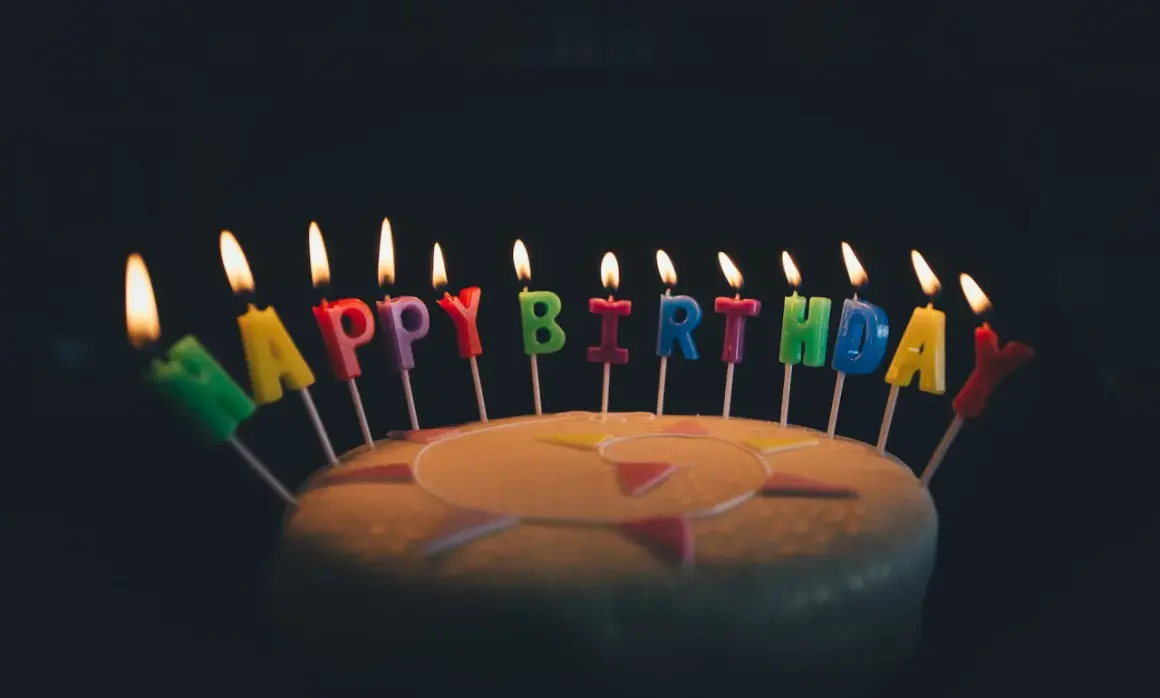 Płonące świeczki z literami tworzą napis "Happy Birthday". Idealne życzenia urodzinowe po angielsku na torcie.
