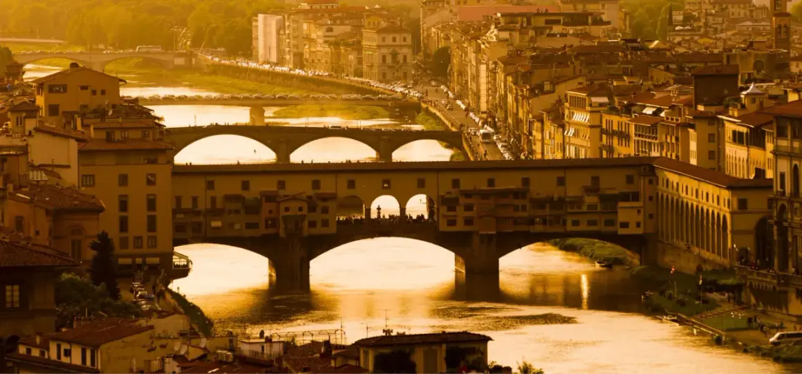 Florencja 18 maja. Złote światło zalewa Ponte Vecchio i rzekę Arno, tworząc malowniczy widok miasta.