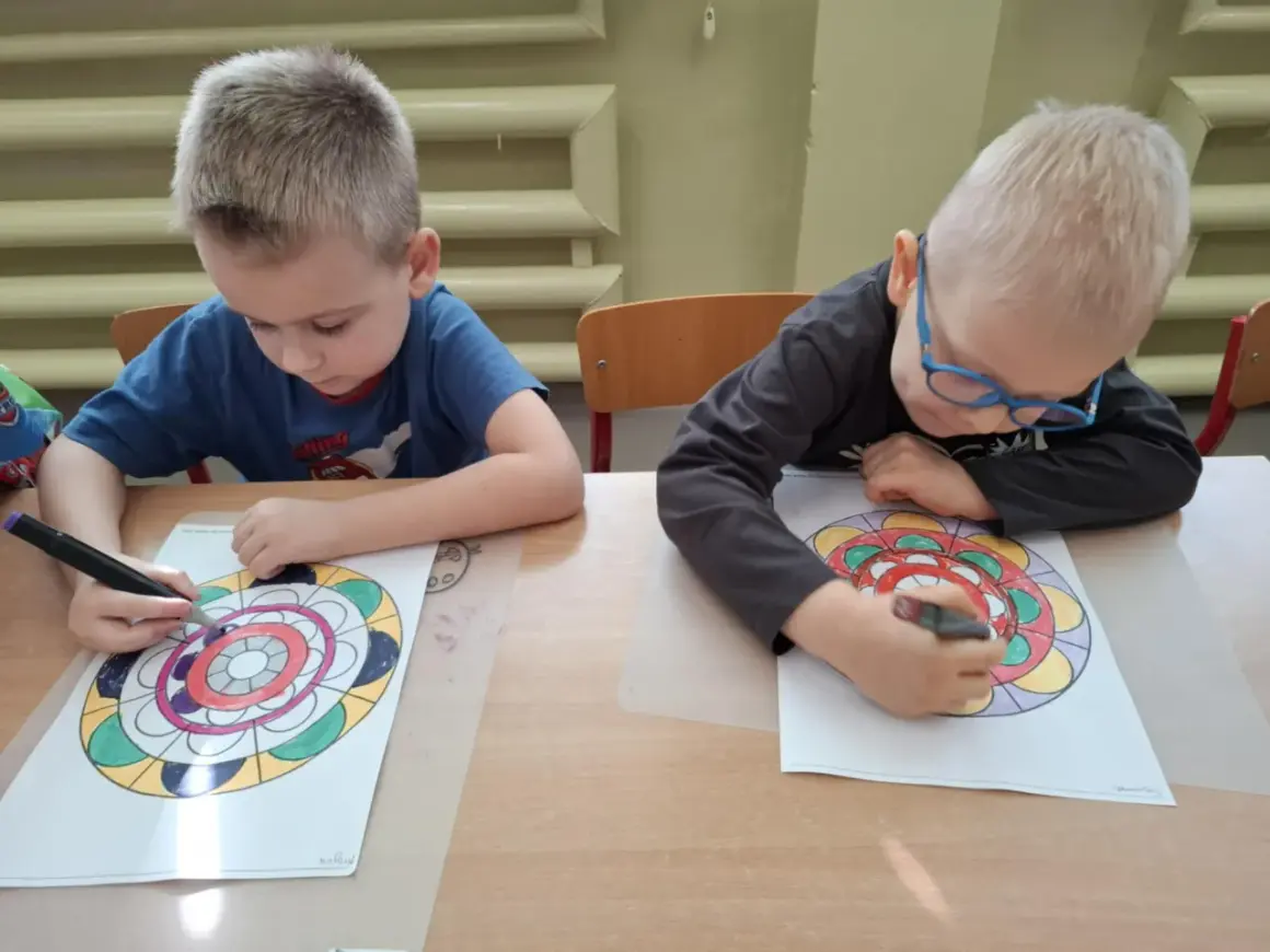 Dwóch chłopców z zapałem koloruje swoje mandale.