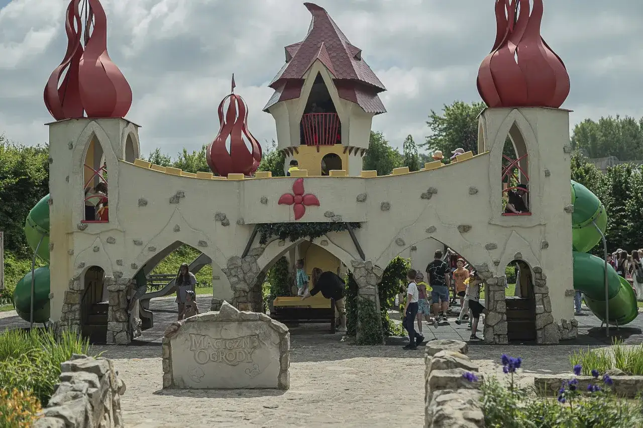 Zamek z czerwonymi kopułami i zjeżdżalniami, idealne miejsce na rodzinne aktywności. Dzieci bawią się na placu zabaw w 