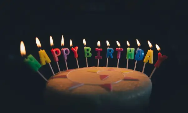 Płonące świeczki z literami tworzą napis "Happy Birthday". Idealne życzenia urodzinowe po angielsku na torcie.