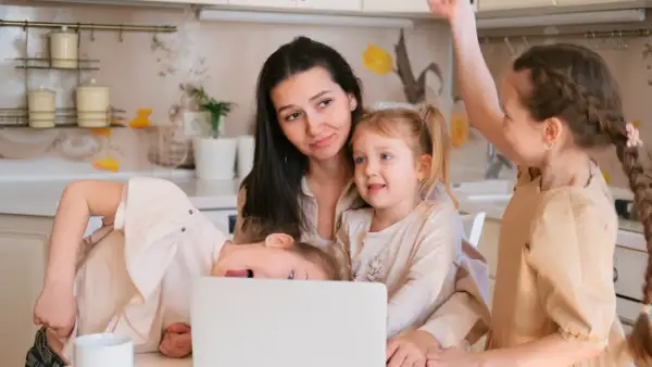 Mama z trójką dzieci przy laptopie. Czy to przyszły dodatek do emerytury za urodzenie 3 dzieci?