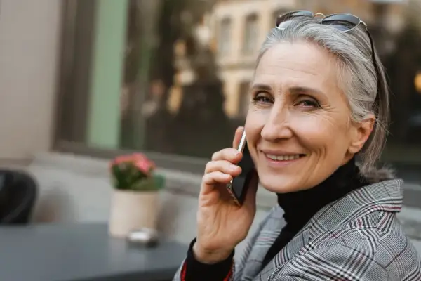Uśmiechnięta Grażyna rozmawia przez telefon, ciesząc się swoim imieninowym dniem.
