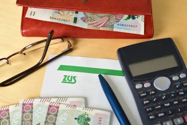 Na stole leżą dokumenty ZUS, pieniądze, kalkulator i okulary. Przygotowanie do złożenia wniosku o świadczenie wspierające.