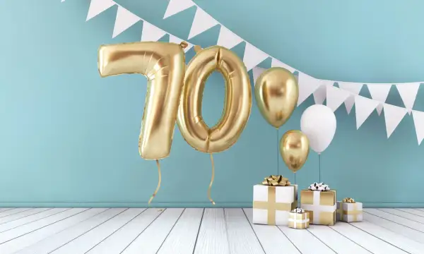 Złote balony z cyfrą 70, prezenty i girlanda tworzą radosną atmosferę. Idealne życzenia na 70 urodziny!