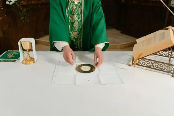 Kapłan przygotowuje się do udzielenia komunii. Na ołtarzu kielich, patena z hostią i księga.