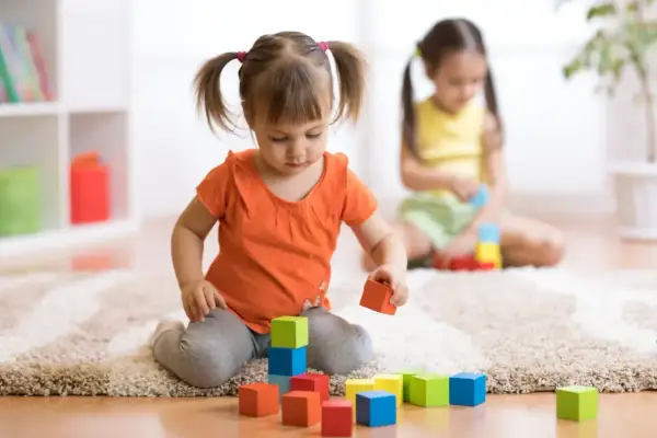 Dwie dziewczynki bawią się klockami. Jedna z nich, z kitkami, układa wieżę. To inwestycja w przyszłość, jak 12 tys na dziecko.