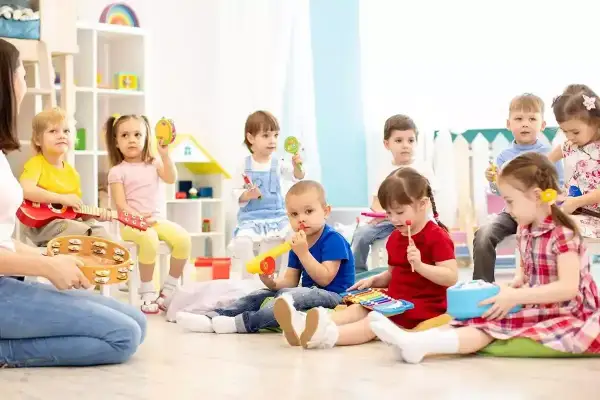 Dzieci na zajęciach muzycznych, grają na instrumentach. Ciekawe, ile zarabia przedszkolanka za taką pracę.